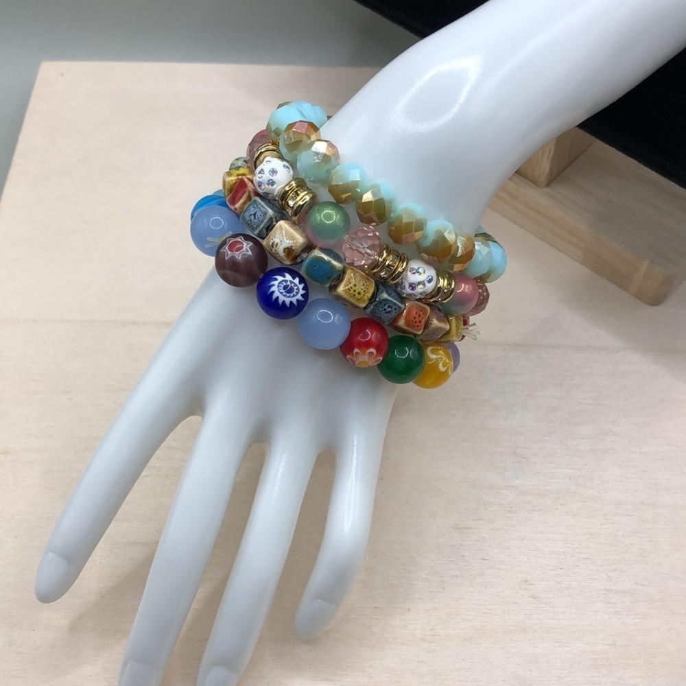 Curated bundle colorful stackable art glass and ceramic bracelets roll on.